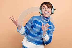 Photo of funky excited lady wear blue pullover headphones having fun looking empty space isolated beige color background