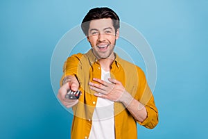 Photo of funky guy hold remote control watch comedy laugh hand chest wear yellow shirt isolated blue color background