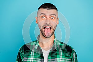 Photo of funky happy positive young man stick out tongue funny face crazy enjoy isolated on blue color background