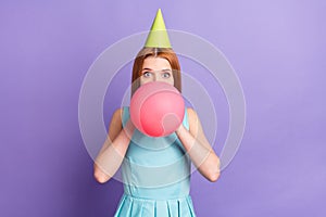 Photo of funky happy young woman blow air balloon party decoration inflate isolated on purple color background