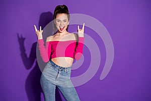 Photo of funky lady raise two arms show horns stick out tongue look camera wear jeans pink cropped top isolated purple