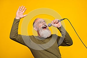 Photo of funky old white beard man sing in mic wear eyewear green sweater isolated on yellow color background