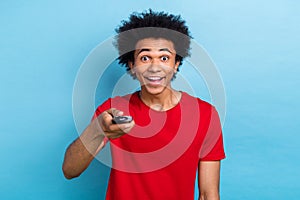 Photo of funky positive man toothy smile hand hold remote tv control switch channel isolated on blue color background