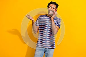 Photo of funky positive man wear trendy striped clothes talk phone uality connection empty space isolated on yellow