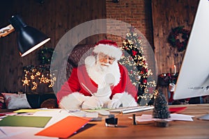 Photo of funky positive santa claus wear red costume writing christmas greetings indoors north pole office