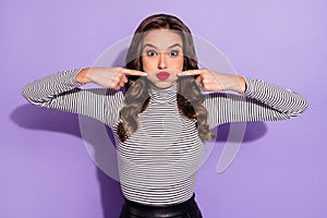 Photo of funny adorable young woman wear striped outfit pointing fingers bloated cheeks isolated violet color background