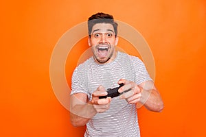 Photo of funny attractive cheerful guy hold hands joystick playing video games excited gamer riding speed car to finish