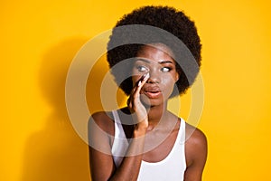 Photo of funny black young girl look empty space palm mouth whisper wear white tank-top isolated yellow color background
