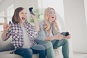 Photo of funny blond lady mom daughter sitting comfy couch joystick play video game winner loser stay home quarantine