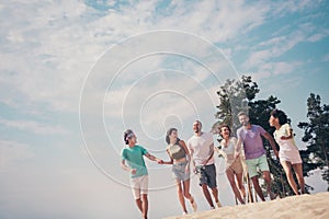 Photo of funny charming six young buddies dressed casual outfits walking holding arms speaking smiling outdoors