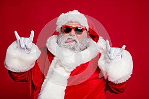 Photo of funny crazy rude careless old man show horns protrude tongue wear santa hat costume isolated red color photo