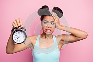 Photo of funny dark skin lady hold metal classic alarm clock hand on head grimacing oversleep missed work afraid to be photo