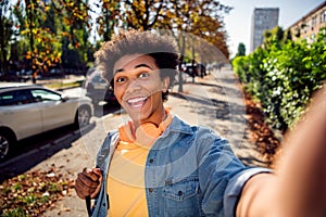 Photo of funny good mood guy wear denim jacket earphones smiling recording video vlogging outside urban city street