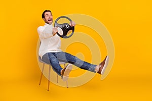 Photo of funny guy hold steering wheel sit chair car incident concept wear white pullover isolated yellow color