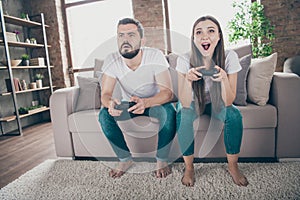 Photo of funny homey mood pair sitting sofa indoors playing video games excited who wins