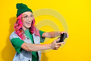 Photo of funny impressed eccentric girl pink hairdo dressed denim waistcoat hold play station joystick isolated on