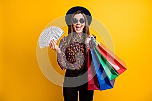 Photo of funny lady hold bags money open mouth wear cap vintage style isolated on yellow color background
