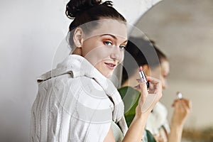 Photo of funny laughing young girl applying lipstick on lips