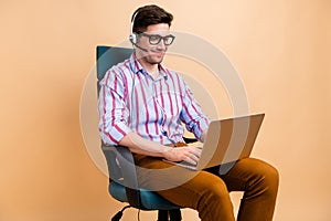 Photo of funny man professional call center worker talking in earphones with microphone laptop isolated on beige color