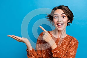 Photo of funny overjoyed business lady directing finger novelty product at open arm isolated over blue color background