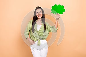 Photo of funny positive nice girl dressed green blouse look at dialog cloud in hand empty space isolated on beige color