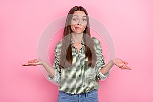 Photo of funny puzzled woman wear striped shirt shrugging shoulders isolated pink color background