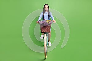 Photo of funny sweet young woman dressed blue outfit driving bike smiling isolated green color background