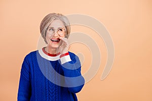 Photo of funny tricky woman with gray hair dressed knit sweater in glasses tell secret look empty space isolated on