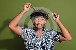 Photo of funny upset man dressed print shirt dislike hairstyle curls isolated green color background