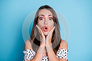 Photo of funny young girl crazy face open mouth palms cheeks wear dotted blouse isolated blue color background