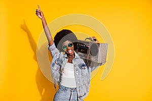 Photo of funny young lady wear casual denim outfit arm glasses holding boombox pointing empty space isolated yellow