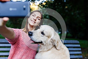 Photo of girl on bench doing selfie with retriever