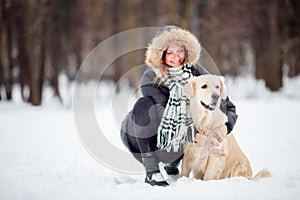 Photo of girl in black jacket squatting next to dog in winter