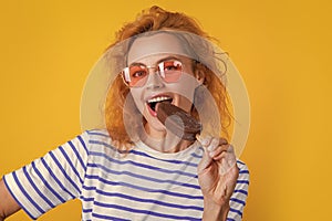 photo of girl eat icelolly ice cream at summer. girl with icelolly ice cream isolated on yellow.