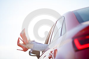Photo of girl`s legs in red shoes sticking out of red car window