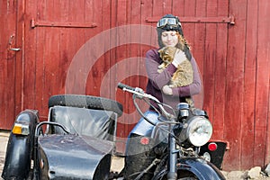 Photo of girl on a vintage motorbike in pilot cap with cat