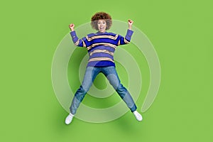 Photo of glad cheerful woman wear blue striped trendy clothes jump up celebrate success isolated on green color