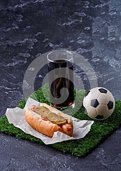 Photo of glass of beer, green grass with soccer ball, hotdog