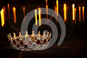 photo of gold crown over gothic dark silk background. Medieval period concept.