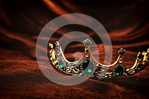 photo of gold crown over gothic dark silk background. Medieval period concept.