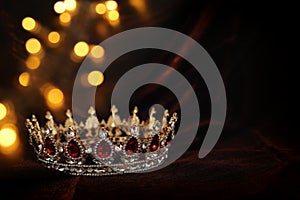 photo of gold crown over gothic dark silk background. Medieval period concept.