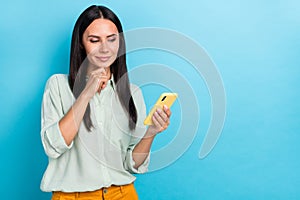 Photo of good looking positive female brainstorming read sms message in cellphone isolated on blue color background