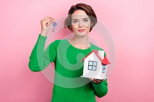 Photo of good mood cute lady wear green pullover buying new house rising keys isolated pink color background