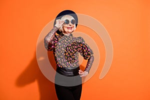 Photo of good mood happy smiling positive old woman look copyspace wear sunglasses isolated on orange color background