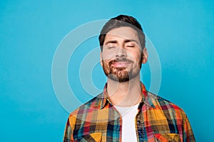 Photo of good mood man with beard dressed checkered shirt close eyes focused on positive thoughts isolated on blue color