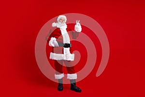 Photo of good mood retired man santa claus showing v-sign magic new year advent spirit isolated on red color background