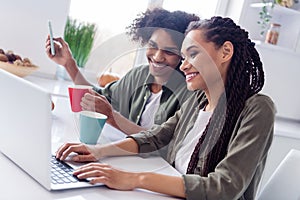 Photo of good mood siblings brother and sister have morning coffee surfing in social media laptop do online shopping