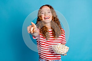 Photo of good mood woman with wavy hairdo dressed striped t-shirt hold popcorn directing at you laugh isolated on blue