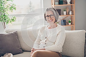 Photo of gorgeous cheerful lady sitting on couch wearing stylish sweater spending weekend at home alone