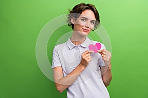 Photo of gorgeous cute girl hand showing pink paper card heart figure empty space isolated on green color background